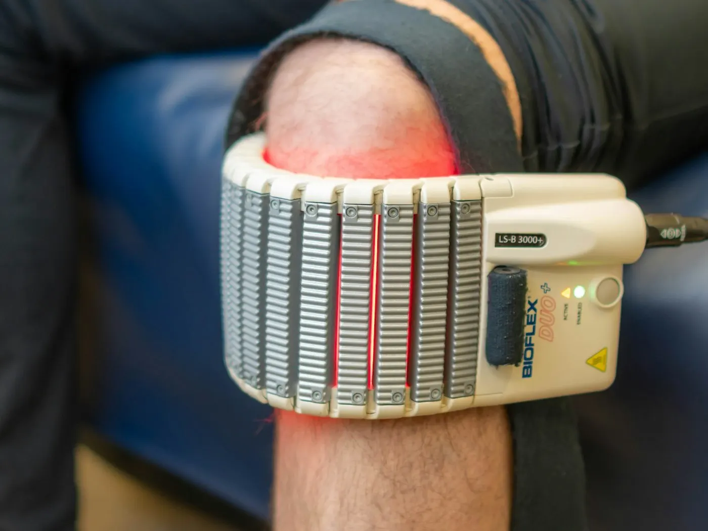A red light therapy pad wrapped around a patient's knee