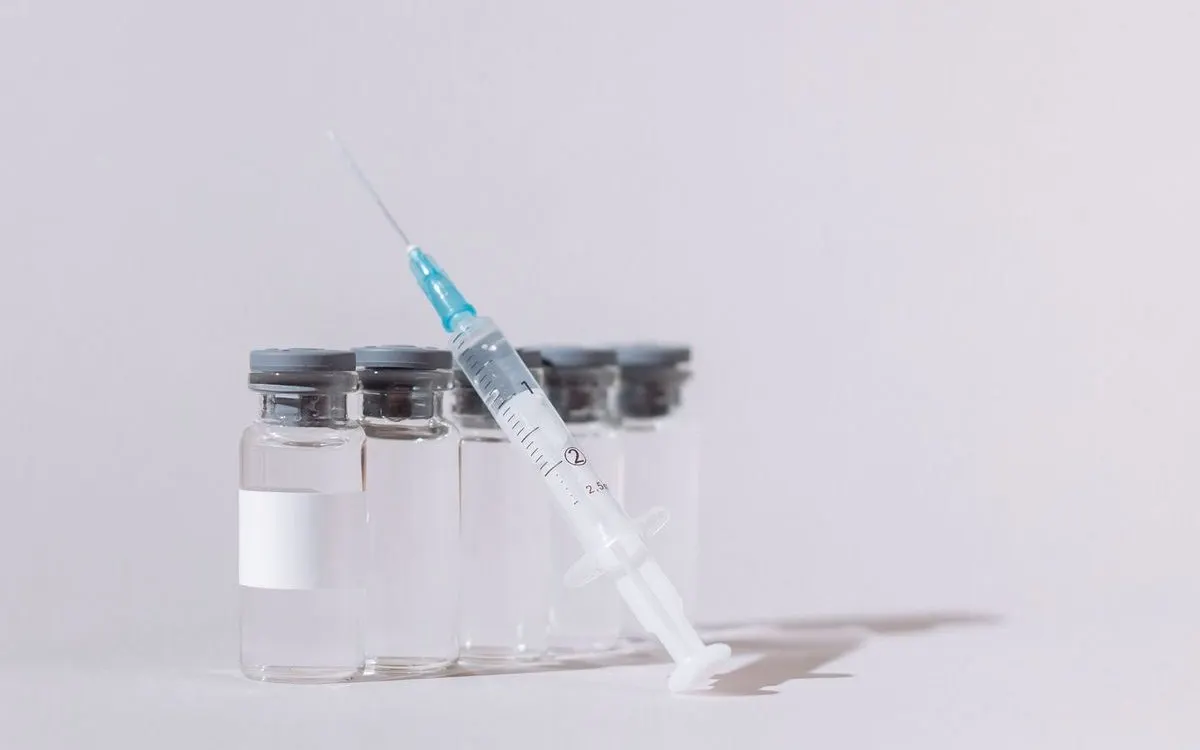 A prepared syringe resting against a row of clear medication vials