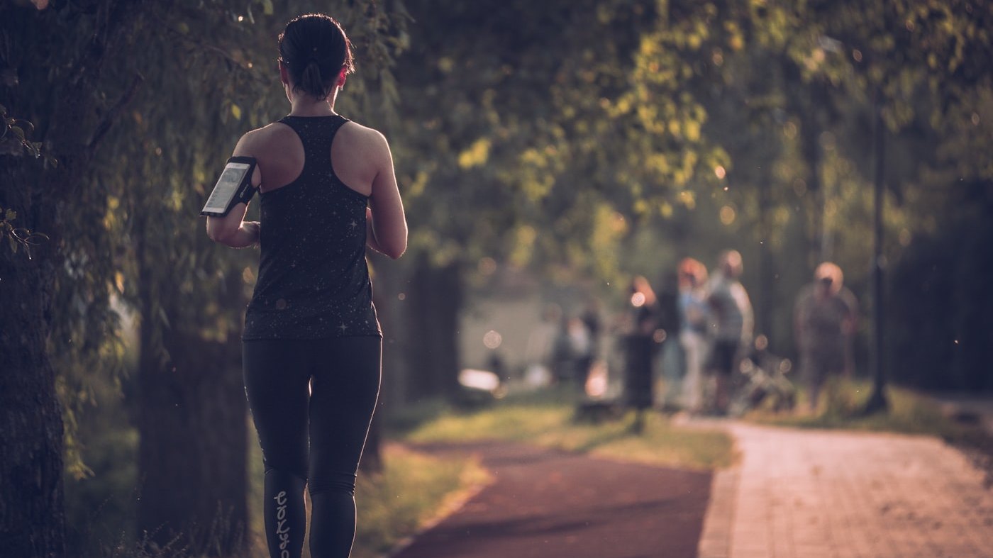 A runner on a tree-lined path in the early evening