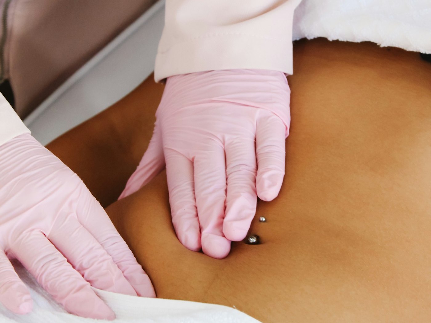 A practitioner's gloved hands positioning a treatment applicator on a patient's abdomen