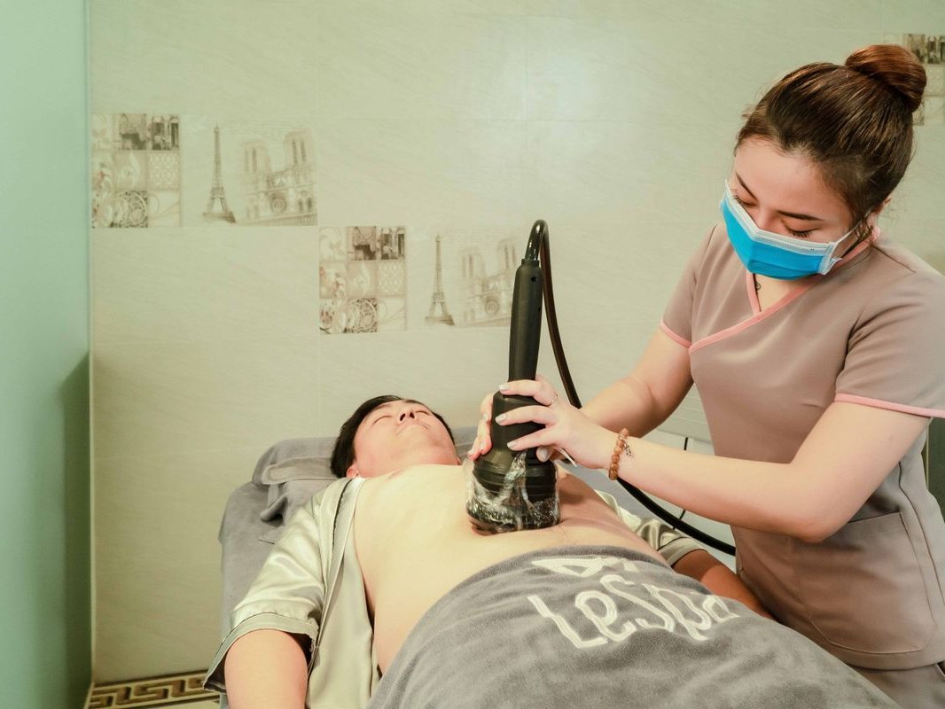 A practitioner guiding a contouring handpiece over a patient's midsection