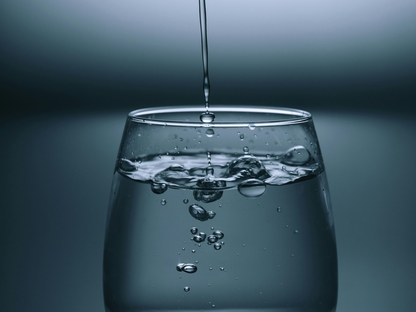Water being poured into a glass on a bright table
