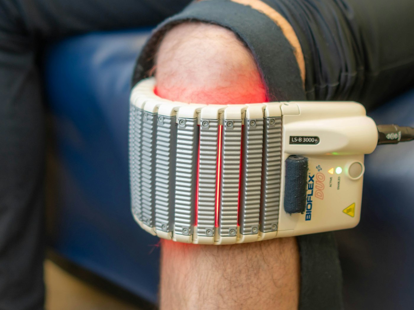 A red light therapy pad wrapped around a patient's knee