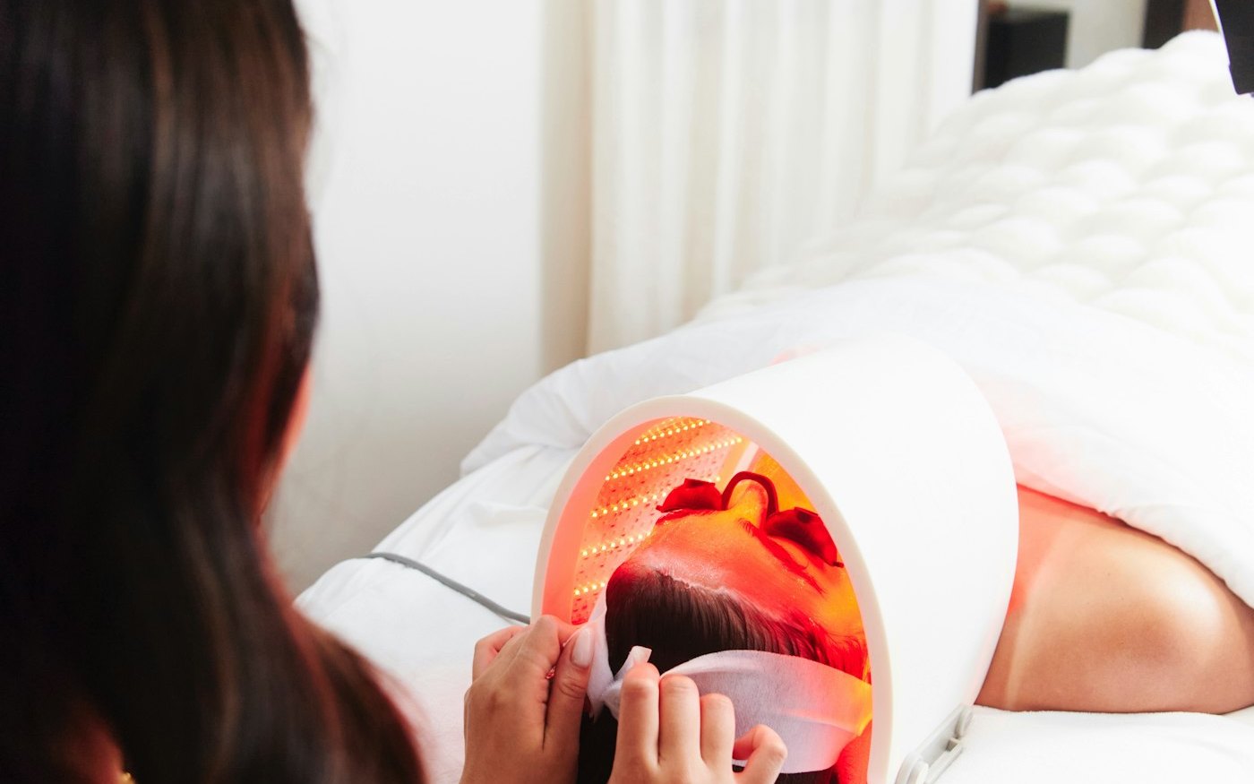 A patient relaxing under a red LED light therapy mask