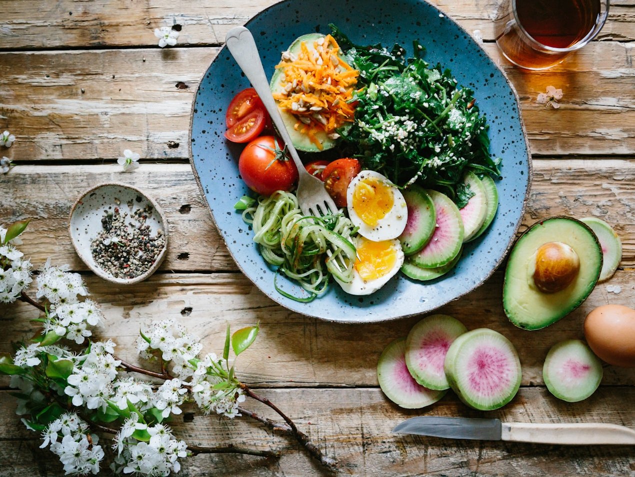 A balanced plate of vegetables, eggs, and whole foods on a wooden table