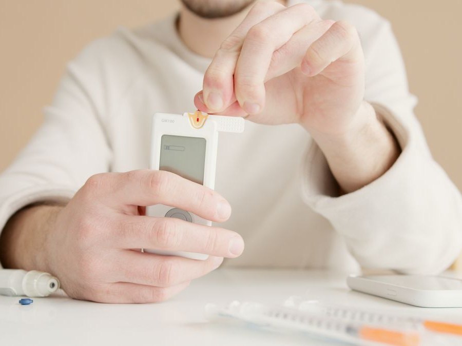 A blood glucose meter and lancet held in a patient's hands