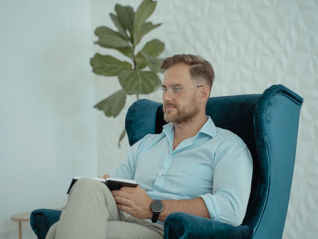 A man sitting comfortably in an armchair, reading