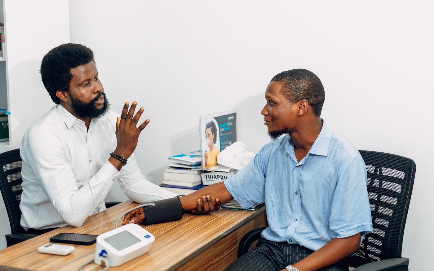 A clinician taking a male patient's blood pressure at the start of a men's health evaluation